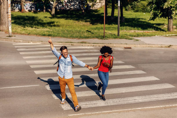 istock Young cheerful couple running over street and smiling. 1267390686