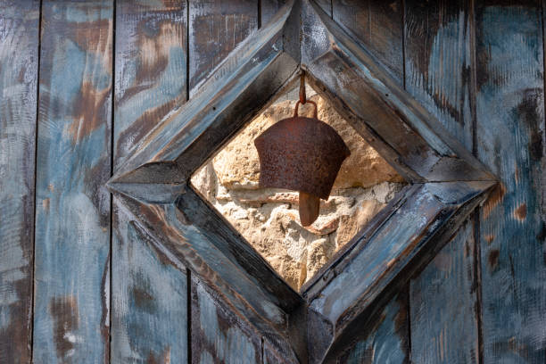 istock A rusty bell hung on an old wooden door. 1267390704