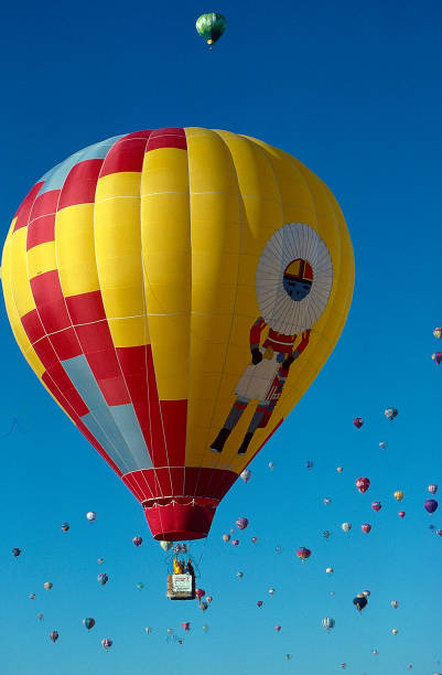 Kachina Balloon Floating in the Air Colorful Hot Air Balloon featuring an image of a Pueblo Kachina as several balloons dot the bright blue morning sky. kachina doll photos stock pictures, royalty-free photos & images