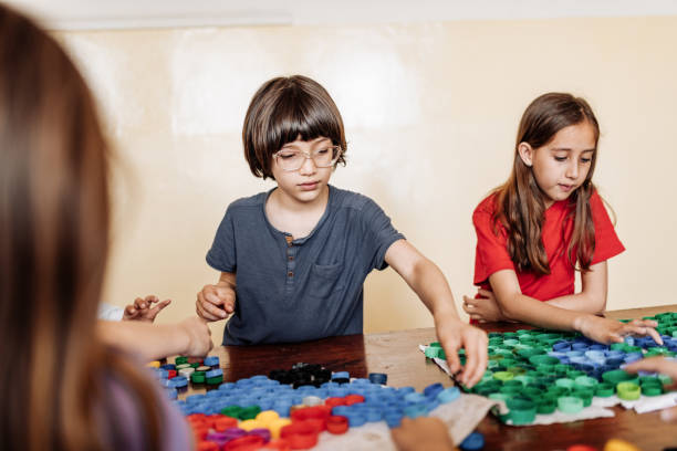 istock Elementary school kids using recycled plastic to create artwork. They are happy to be together again after coronavirus. 1267395898