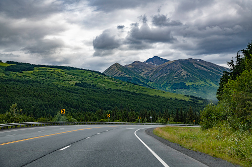 Landscape view of mountains and highway on Kenai peninsula on cloudy and rainy day.