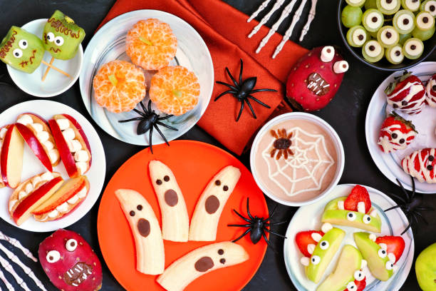 istock Healthy Halloween fruit snacks. Top view table scene over a black stone background. 1267397092