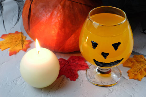 istock Halloween composition with drink, orange cocktail, pumpkin, candle and fallen leaves, selective focus 1267397646