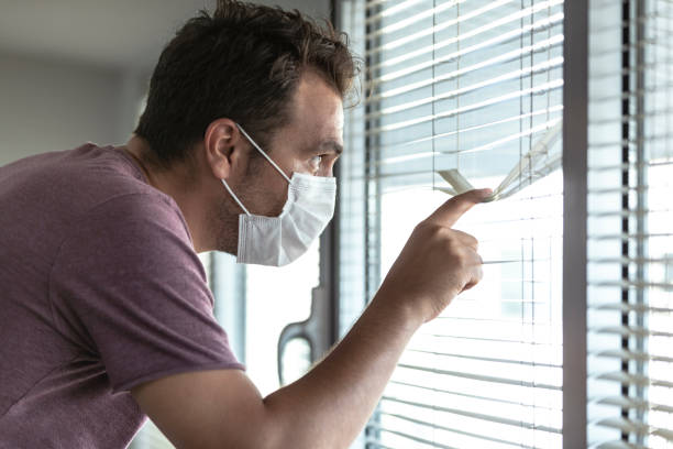 man looking from behind shutters during quarantine time in hospital. coronavirus quarantine isolation scene - infuse imagens e fotografias de stock