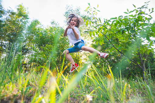 Happy child enjoying the good weather in the backyard. Summer, spring. Social isolation during the COVID-19 pandemic.