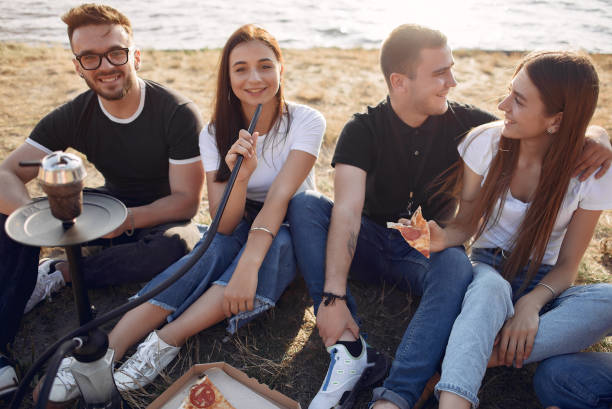 istock Young people eating pizza smoking shisha outside 1267407239