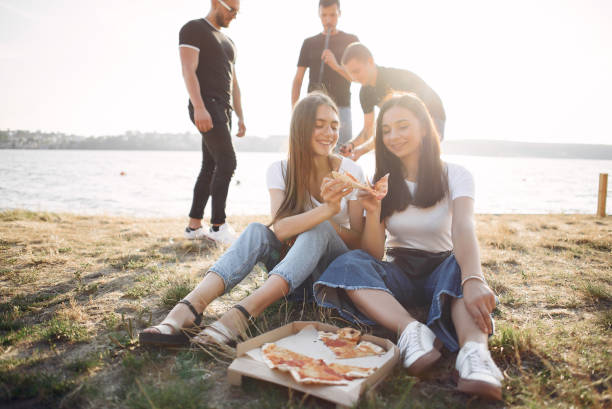 istock Young people eating pizza smoking hookah outside 1267407329
