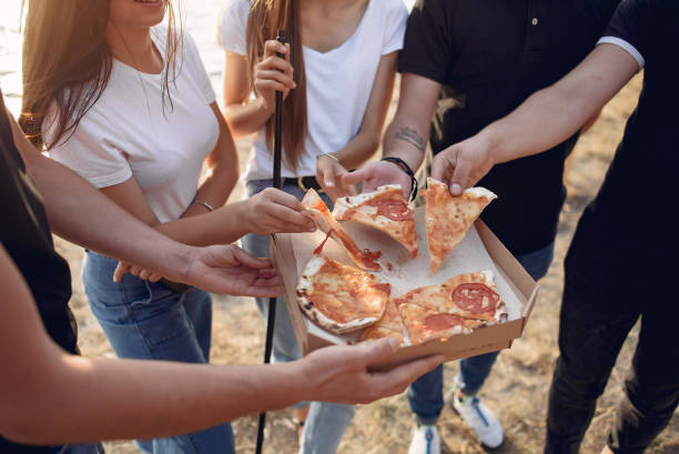 istock Young people eating pizza smoking hookah outside 1267407371