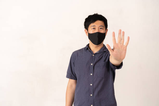 istock Asian man wearing face mask with hand palm raised towards camera 1267414711