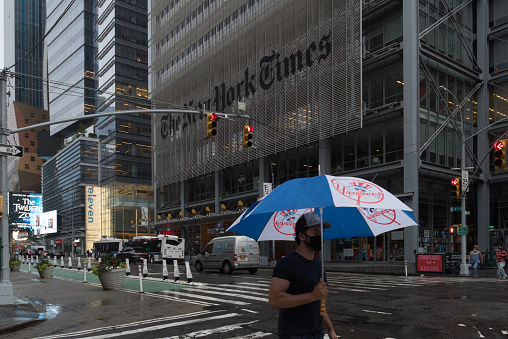 Manhattan, New York. July 10, 2020. A man wearing a mask walks in front of the New York Times building in Midtown.