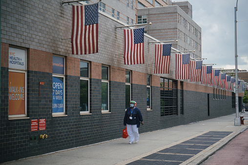 Queens, New York. July 01, 2020. A hospital worker wearing a face mask walks by the Elmhurst Hospital Center.