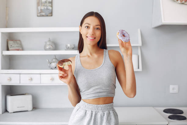 istock Beautiful girl standing in a kitchen with donut 1267426651