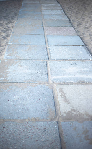 istock A path made of gray stone tiles with sand. 1267428734