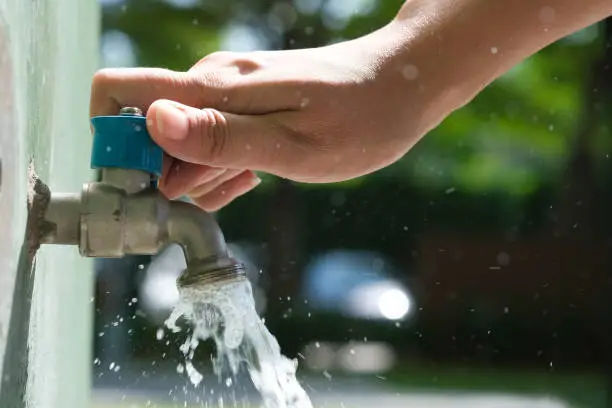 Photo of hand of woman she was using her hand to shut the flowing water from faucet.water saving and energy ideas