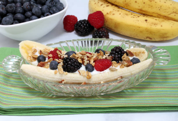Fruit and yogurt fruit salad with granola and nuts styled as a banana split.