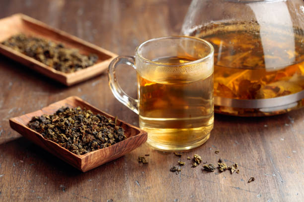 горячий зеленый чай в стеклянной кружке. сушеные чайные листья и горячий напиток на деревянном столе. - 5954 стоковые фото и изображения