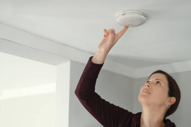 Young adult woman checking fire alarm stock photo