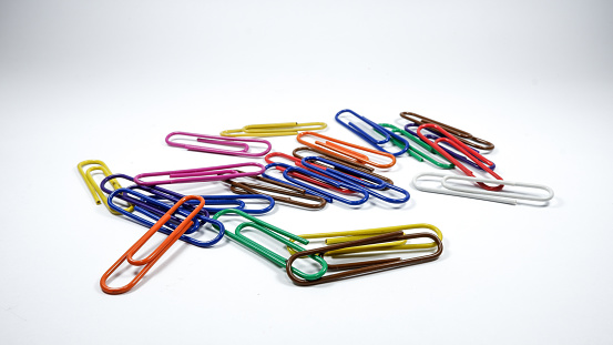 Heap / stack of multi-colored paper clips on white background