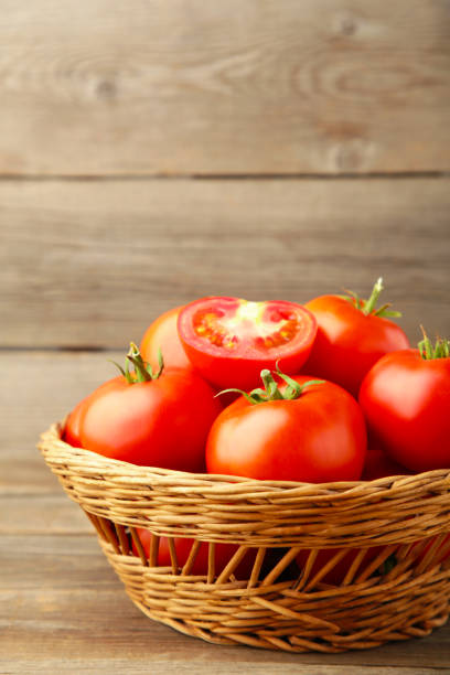 istock Ripe red tomatoes in basket on grey wooden background. 1267456344