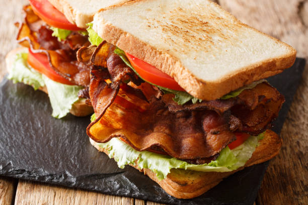 popular aperitivo americano blt sándwiches con tocino crujiente, ensalada fresca y tomates de cerca en una tabla de pizarra. horizontal - sandwich delicatessen bacon lettuce and tomato mayonnaise fotografías e imágenes de stock