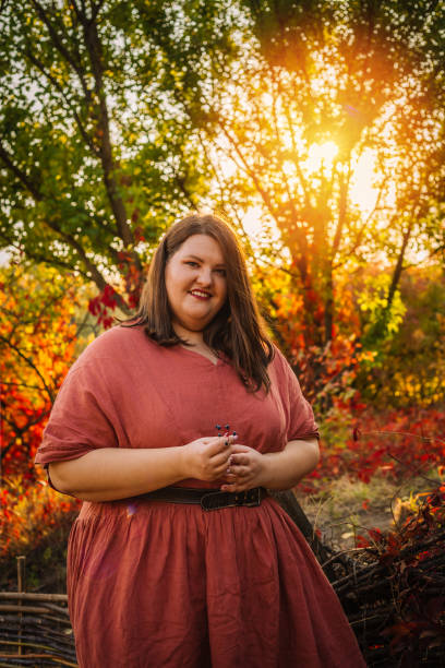 istock Beautiful and confident plus size model in red dress and brown boots  posing outdoors at autumn landscape 1267456536