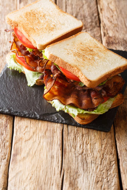 sándwiches caseros con tocino crujiente, ensalada fresca y tomates de cerca en una pizarra. vertical - sandwich delicatessen bacon lettuce and tomato mayonnaise fotografías e imágenes de stock