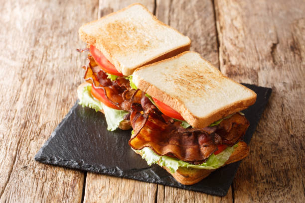 istock Two blt sandwiches with bacon, fresh salad and tomatoes are served on a slate board. horizontal 1267456789