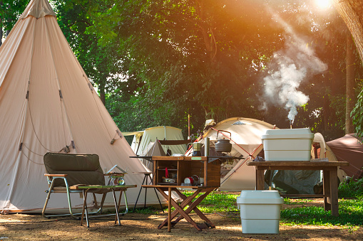 Outdoor kitchen equipment and wooden table set with field tents group in camping area at natural parkland