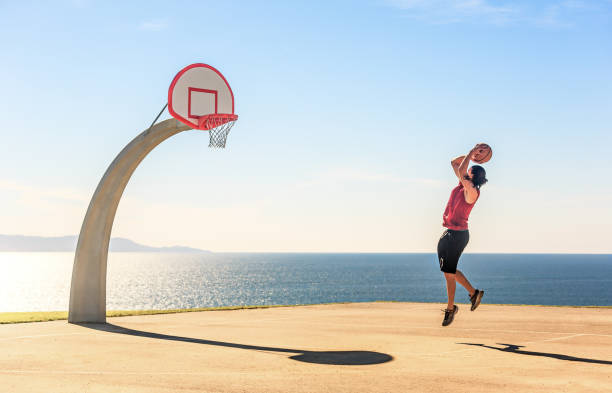 basketballspieler schießen den ball auf den korb reifen in einem schönen outdoor-platz in der nähe des ozeans. - basketball teenager nature outdoors stock-fotos und bilder