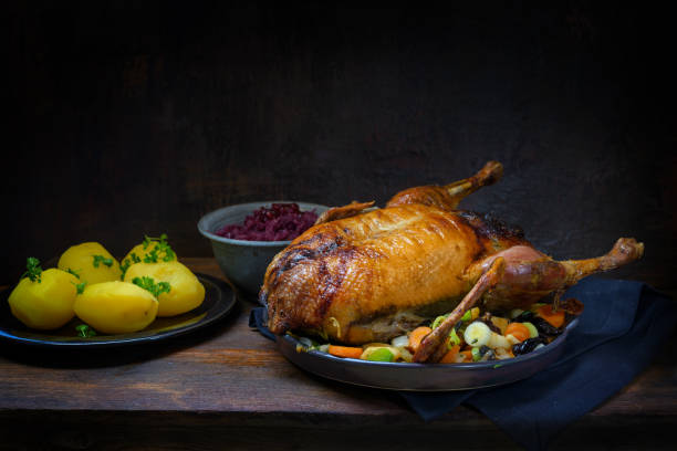 istock Roasted duck with potatoes and red cabbage, a festive meal on a rustic wooden table, dark brown background with copy space, selected focus, narrow depth of field 1267462986