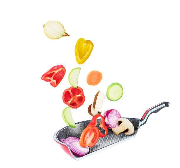 istock Sliced vegetables falling into a cut pan and cooking isolated on white background 1267470822