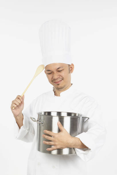 istock Asian chef holding a stew pot and a wooden spoon,looking stressed 1267472198