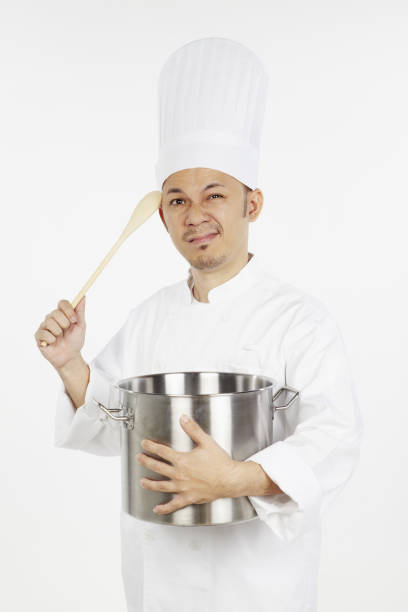 istock Asian chef holding a stew pot and a wooden spoon,looking stressed 1267473571