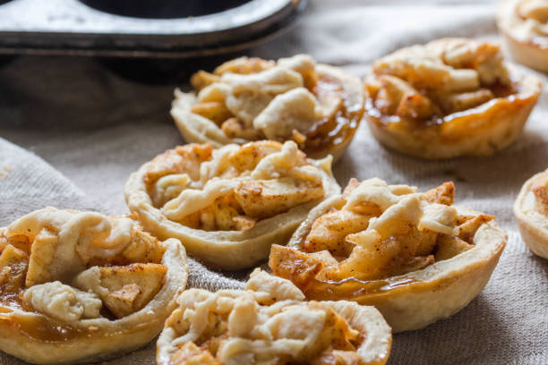istock apple pies with cinnamon and dough decoration - apple tartlets close up 1267473580