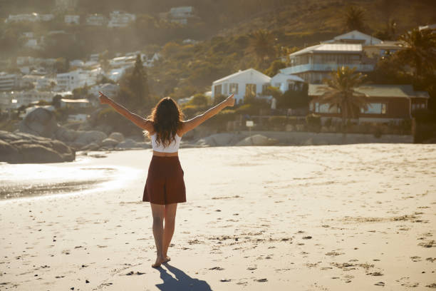Rearview shot of a beautiful young woman with thumbs up on the beach.