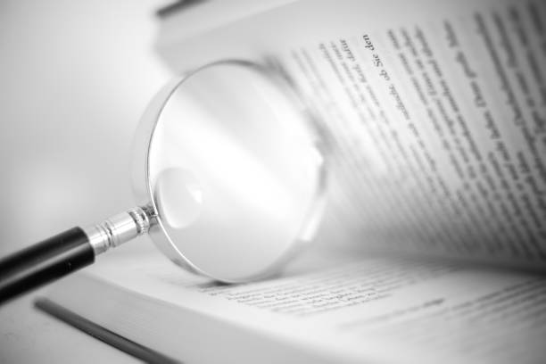 istock Open book with a magnifying glass - black and white 1267478170