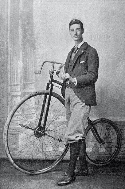 Cyclist F.W. Shorland, England, standing aside of his bicycle, dressed elegantly Illustration from 19th century penny farthing bicycle stock illustrations