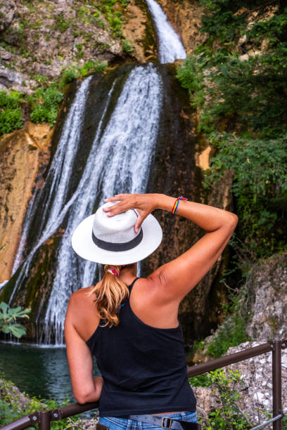 istock Woman wearing a hat poses on her back in front of a waterfall 1267483862