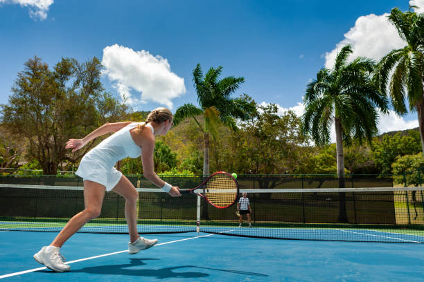 couple playing tennis in tropical climate couple playing tennis in tropical climate, st. john, virgin islands st john's plant stock pictures, royalty-free photos & images