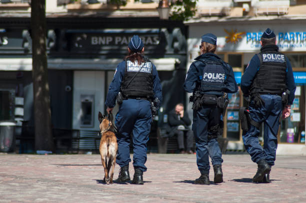 Municipal Police patrolling on cobbles place on back view Mulhouse - France - 13 May 2019 - Municipal Police patrolling on cobbles place on back view mulhouse photos stock pictures, royalty-free photos & images