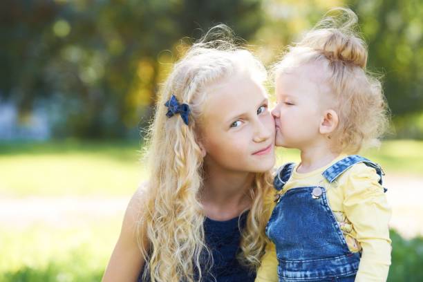 Sisters. Relations. Daughters. Portrait of children. Kiss. Love