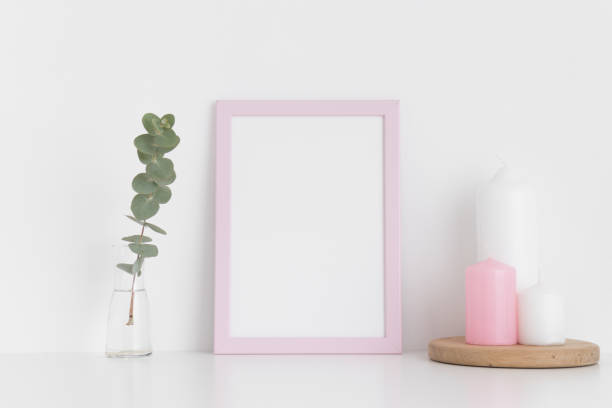 istock Pink frame mockup with candles and eucalyptus in a vase on a white table. Portrait orientation. 1267490084