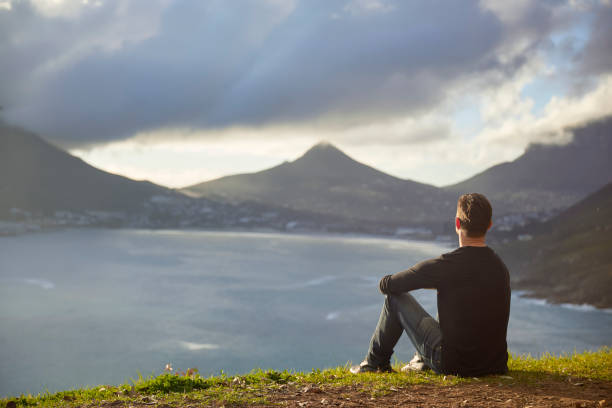 istock Young man contemplating view from top cliff 1267492369