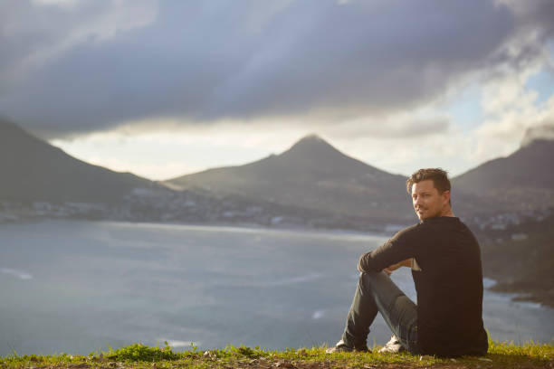 istock Young man contemplating view from top cliff 1267492448