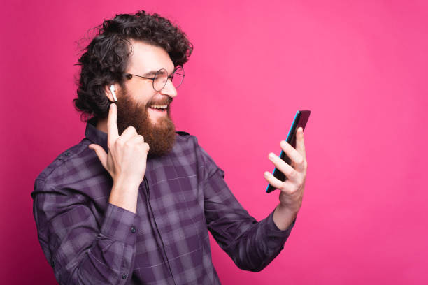 istock Portrait of cheerful curly guy using earpods and looking at tablet 1267492599