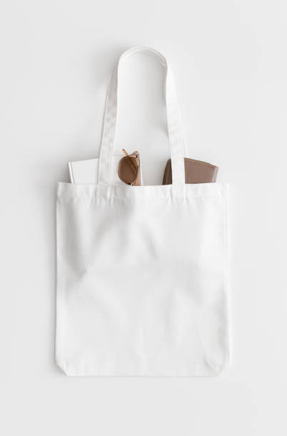 istock White tote bag mockup with a book, wallet and glasses on a white table. 1267495281