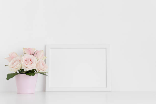 istock White frame mockup with pink roses in a pot on a white table.Landscape orientation. 1267498820