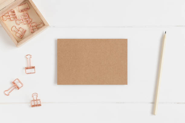 istock Top view of a craft card mockup with workspace accessories on a white table. 1267500088