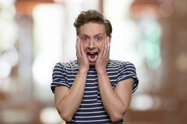istock Scared teen boy is screaming on abstract blurred background. 1267500773
