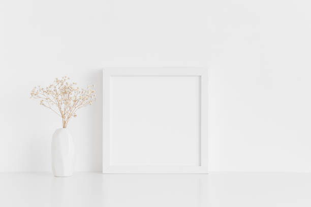 istock White square frame mockup with a gypsophila in a vase on a white table. 1267500928